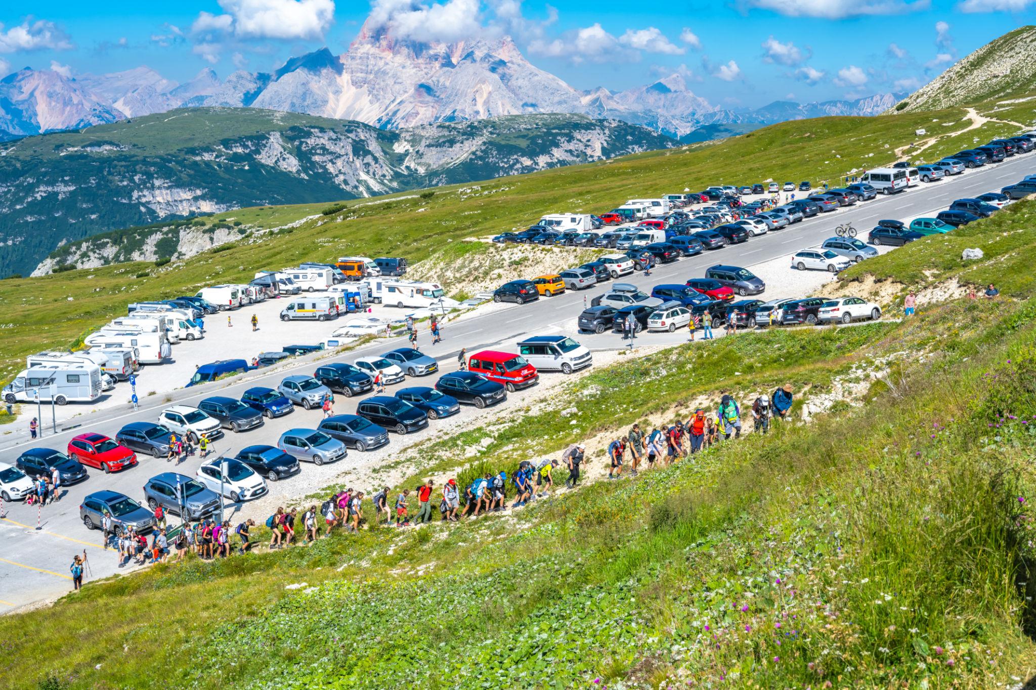 Auto, camper e visitatori affollano una strada in alta montagna